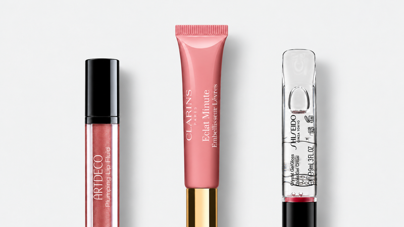 Lesky na rty — Artdeco Plumping Lip Fluid 28 Goddess 3 ml, Clarins Lip Perfector 12 ml, Shiseido Crystal GelGloss 9 ml; tři produkty na světlém šedém pozadí