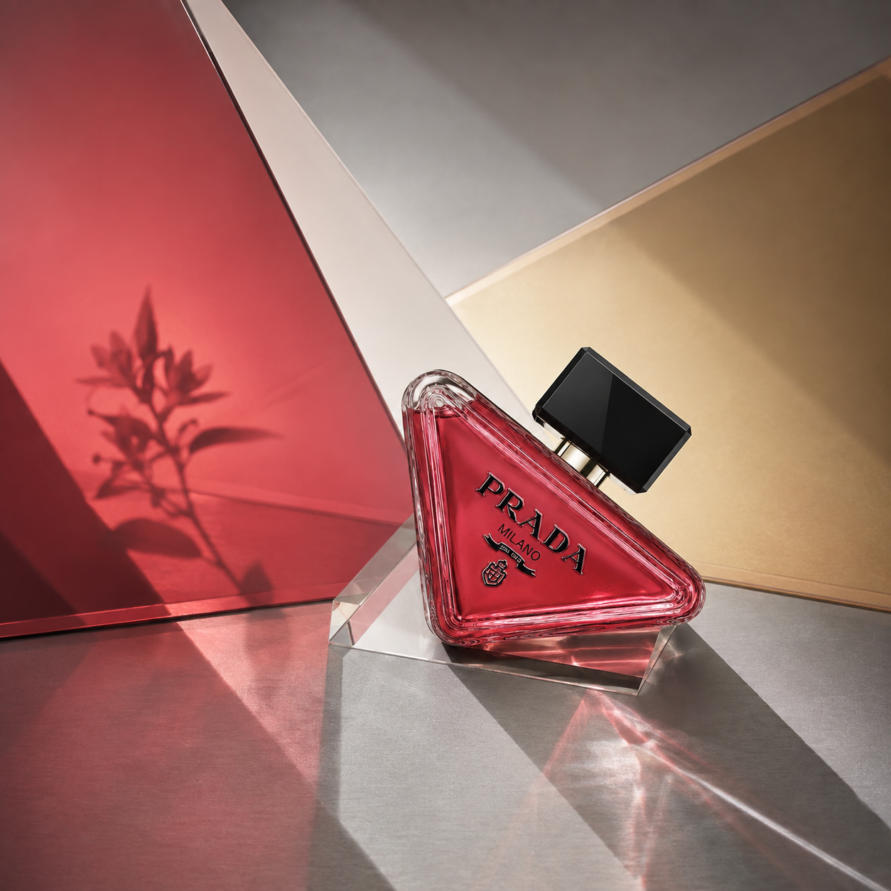 Prada Paradoxe Radical Essence EDP na skleněném hranolu před červenými a zlatými plochami se stínem květiny – MrRizz